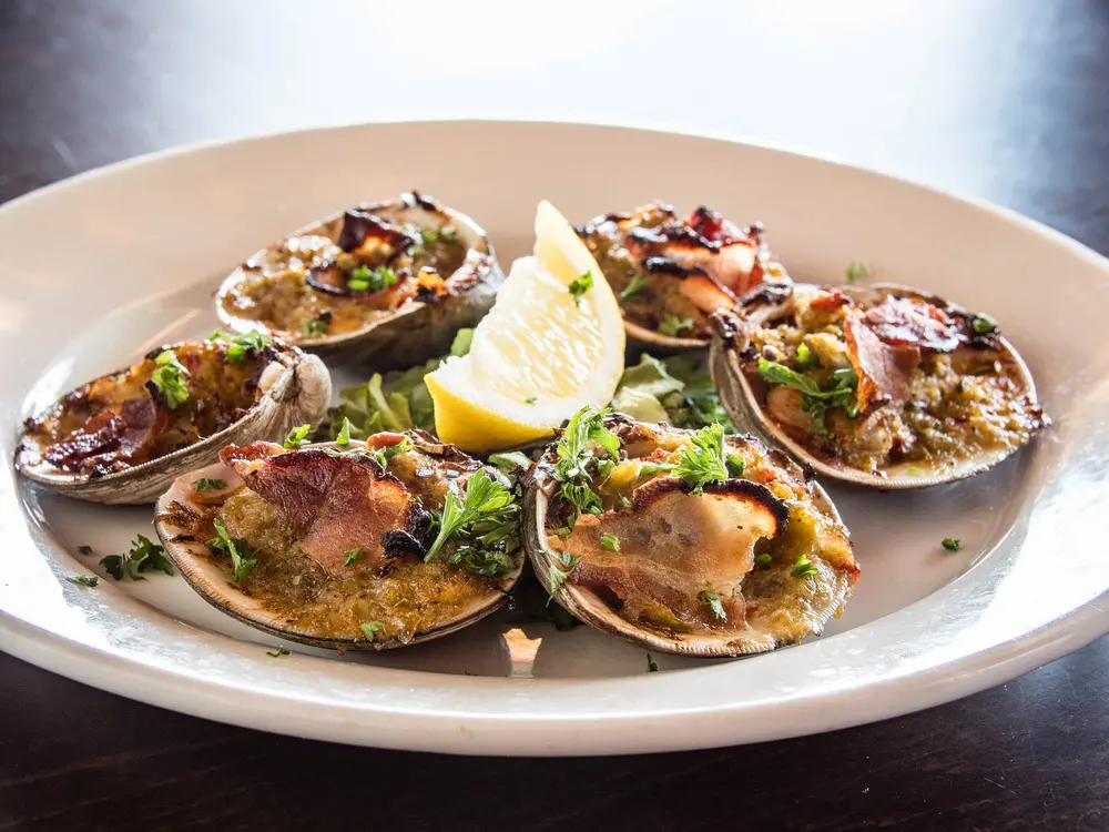 Clams on a plate with lemon and cocktail sauce
