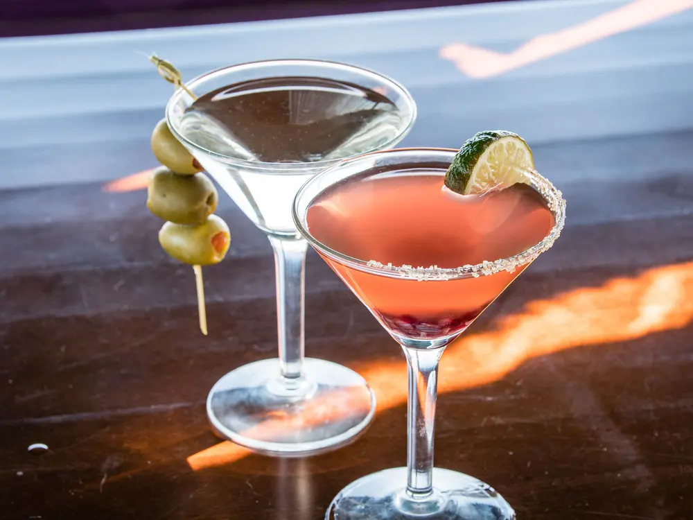 Two cocktails in martini glasses, one with a salted rim and lime
